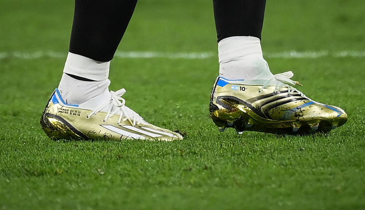 Sepatu Lionel Messi itu sebagian besar berwarna emas, dengan biru dan putih mewakili warna bendera Argentina. Ada pula garis hitam di bagian belakang dan tiga garis putih corak khas Adidas. (AFP/Franck Fife)