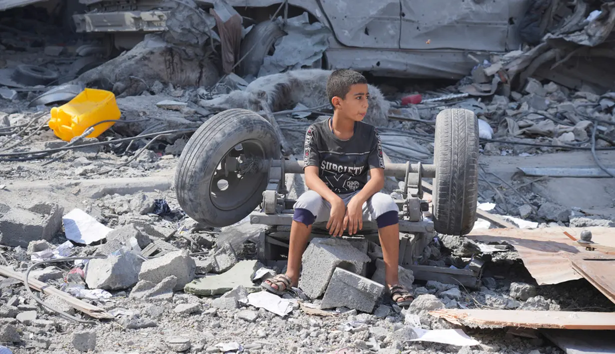 Seorang anak laki-laki Palestina duduk di reruntuhan bangunannya yang hancur akibat serangan udara Israel di Kamp Nuseirat, Jalur Gaza, Palestina, 16 Oktober 2023. (AP Photo/Hatem Moussa)
