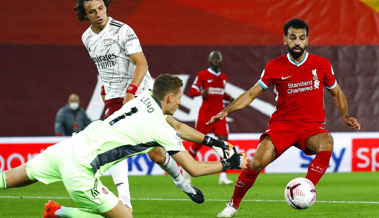 Kiper Arsenal, Bernd Leno, berusaha menghalau tendangan penyerang Liverpool, Mohamed Salah, pada laga Liga Inggris di Stadion Anfield, Senin (28/9/2020). Liverpool menang dengan skor 3-1. (Jason Cairnduff/Pool via AP)