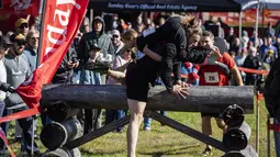 John Lund menggendong Karen May melewati rintangan selama North American Wife Carrying Championship di Sunday River Resort di Newry, Maine, pada 8 Oktober 2022. Kejuaraan ini seakan menguji pengorbanan para suami yang rela menggendong istrinya dengan melewati berbagai rintangan. (Joseph Prezioso / AFP)