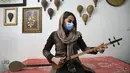 Musisi Sheida Hosseinkhani mencoba alat musik petik bernama Setar buatan Luthier Ali Akbar Soleimani di bengkel kerjanya di Teheran, Iran pada 28 Januari 2021. Tak sedikit musisi yang memesan langsung alat musik tradisional kepada Soleimani. (AP Photo/Vahid Salemi)