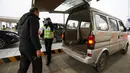 Polisi menggunakan termometer digital untuk mengukur suhu pengemudi mobil di sebuah pos pemeriksaan gerbang tol di Wuhan, Provinsi Hubei, China, Kamis (23/1/2020). Pemerintah China mengisolasi Kota Wuhan yang berpenduduk sekitar 11 juta jiwa untuk menahan penyebaran virus corona. (Chinatopix via AP)