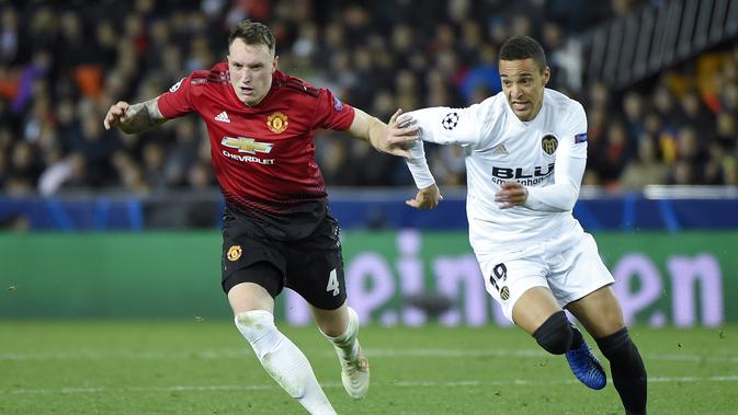 Bek Manchester United, Phil Jones melewati pemain Valencia, Rodrigo Moreno pada laga terakhir grup H Liga Champions yang berlangsung di stadion Mestalla, Valencia, Rabu (13/12). Manchester United kalah 1-2 atas Valencia. (AFP/Jose Jordan)