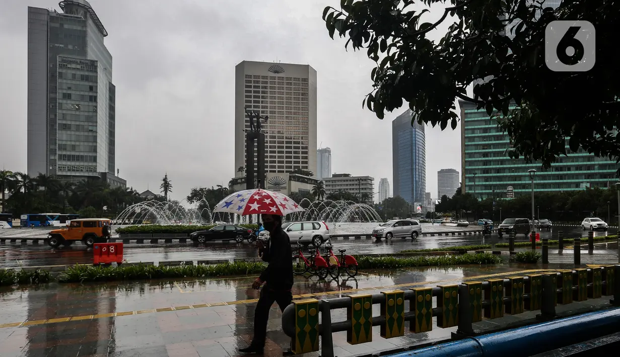 Pejalan kaki menggunakan payung saat hujan di kawasan Jakarta, Selasa (16/2/2021). Setelah memulai vaksinasi COVID-19 tahap pertama dengan sasaran petugas kesehatan, kini pemerintah menargetkan lansia dan petugas pelayanan publik untuk penerima vaksinasi tahap kedua. (Liputan6.com/Johan Tallo)