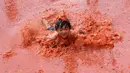 Seorang anak melompat ke dalam kolam berisi tomat selama Festival Tomat di Hwacheon, Korea Selatan, 5 Agustus 2017. Festival untuk merayakan panen tomat ini berlangsung dari 4 - 7 Agustus. (AP Photo/Ahn Young-joon)