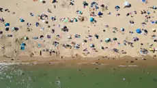 Foto udara menunjukkan orang-orang bermain dan bersantai di bawah sinar matahari di Pantai Bournemouth, Selatan Inggris pada Selasa 26 Mei 2026, saat kondisi gelombang panas menyebar ke sebagian wilayah tenggara Inggris dan London. (JUSTIN TALLIS/AFP)