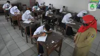 Guru mengajar para murid saat pelaksanaan uji coba pendidikan tatap muka (PTM) di SMPN 15, Kota Bogor, Jawa Barat, Senin (31/5/2021). Pemerintah Kota Bogor menggelar uji coba PTM di 37 sekolah hari ini dengan protokol kesehatan yang ketat. (merdeka.com/Arie Basuki)