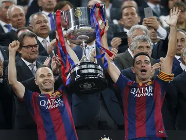 Gelandang Barcelona, Xavi Hernandes (kiri) dan Andres Iniesta mengangkat trofi Copa del Rey usai memenangkan Final Piala Raja di Nou Camp, Spanyol (31/5/2015). Barcelona berhasil menaklukkan Bilbao dengan skor akhir 3-1. (Reuters/Albert Gea)