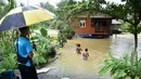 Dinas kedaruratan Thailand menyampaikan bahwa banjir berdampak pada lebih dari 2 juta orang, dengan banjir di Hat Yai dilaporkan merupakan yang terburuk dan berdampak pada 250.000 lebih keluarga. Tampak dalam foto, anak-anak bermain di tengah banjir di daerah Ban Yakang, distrik Mueang, provinsi Narathiwat, Thailand selatan, pada Selasa 25 November 2025. (Madaree TOHLALA/AFP)