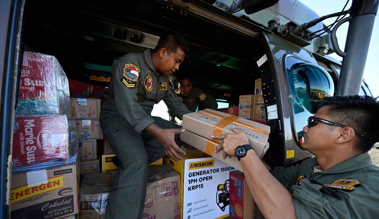 Dari Posko Terpadu Penanggulangan Bencana yang berpusat di Lanud Sultan Iskandar Muda, bantuan dikirim sepanjang hari melalui jalur udara, menjangkau daerah-daerah yang terisolasi akibat cuaca ekstrem dan rusaknya akses. Tampak dalam foto, personel TNI AU memuat pasokan yang akan didistribusikan kepada warga di wilayah terdampak banjir ke dalam helikopter di Pangkalan Udara (Lanud) Sultan Iskandar Muda di Blang Bintang, Aceh Besar pada Kamis 4 Desember 2025. (CHAIDEER MAHYUDDIN/AFP)
