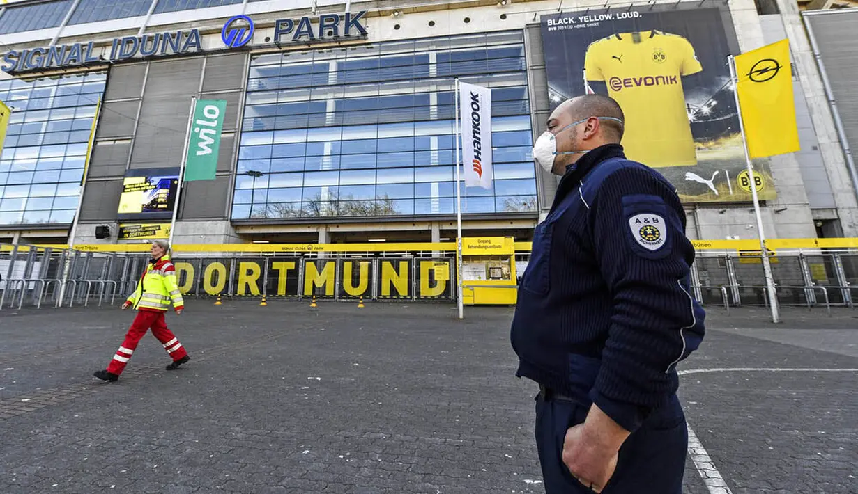 Petugas Keamanan dengan menggunakan masker berjaga di depan Stadion Signal Iduna Park, Jerman, Sabtu (4/4/2020). Stadion Borussia Dortmund ini dialihfungsikan menjadi tempat pusat pengujian COVID-19. (AP/Martin Meissner)