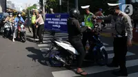 Polisi memberhentikan pengendara sepeda motor saat penyekatan masa PPKM Darurat di Perempatan Fatmawati, Jakarta, Senin (12/7/2021). Penyekatan berlangsung hingga pukul 10.00 WIB. (merdeka.com/Arie Basuki)
