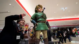 Seorang lelaki berpose di sebelah Link, salah satu karakter Legend of Zelda, permainan legendaris dari Nintendo selama pratinjau pers di toko baru Nintendo di Tokyo, 19 November 2019. Nintendo akan meresmikan toko pertamanya di ibu kota Jepang tersebut pada pekan ini. (Behrouz MEHRI/AFP)