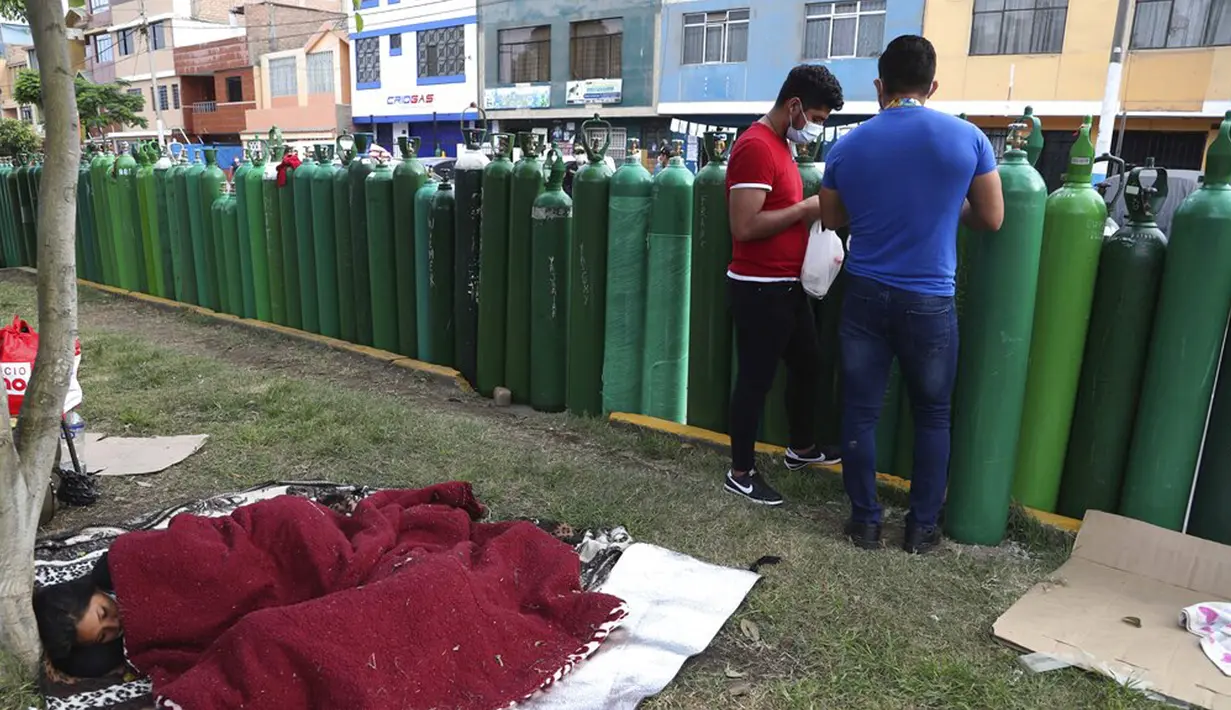 Sejumlah orang tidur di samping tangki oksigen kosong saat menunggu toko isi ulang buka di Callao, Peru, Senin (25/1/2021). Di tengah pandemi COVID-19, beberapa orang mengatakan mereka telah antre sehari sebelumnya untuk menjadi yang pertama saat toko buka. (AP Photo/Martin Mejia)