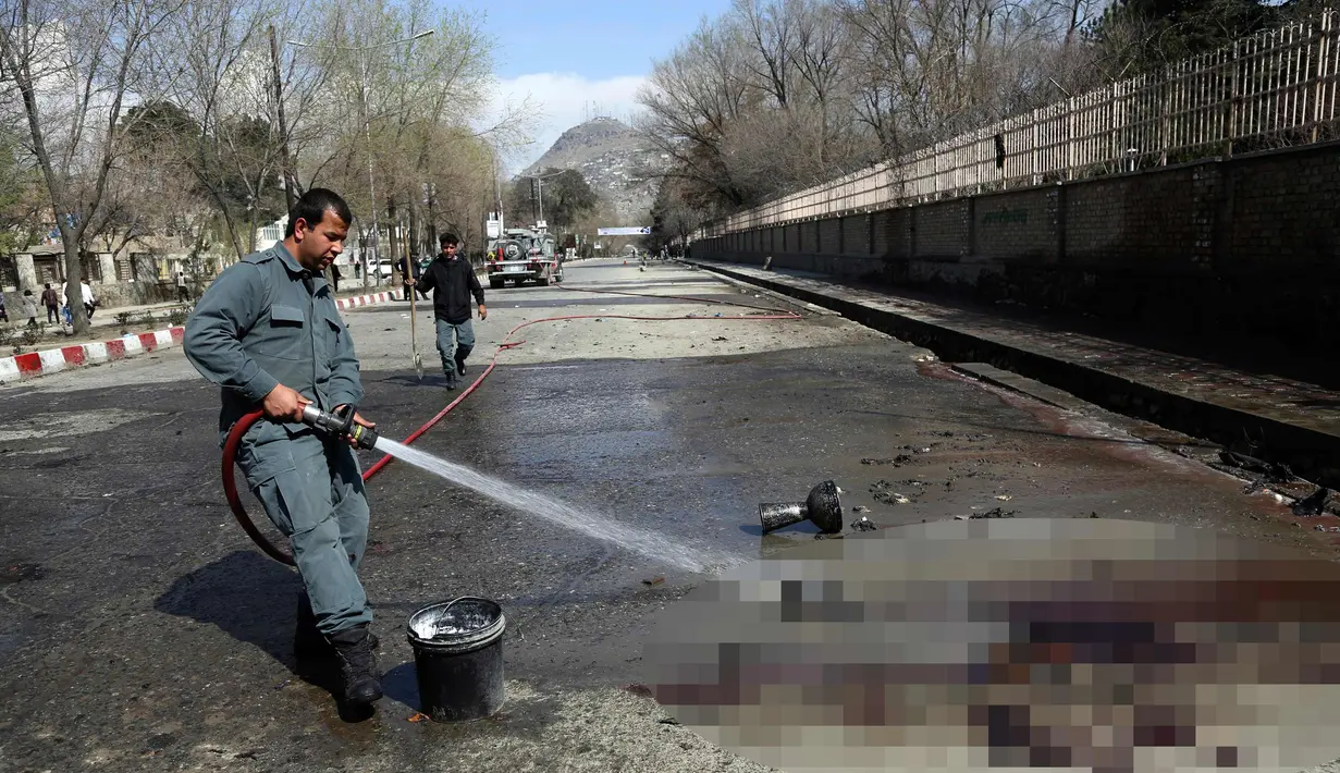 Petugas pemadam kebakaran membersihkan lokasi pemboman bunuh diri di dekat Universitas Kabul, Afghanistan, (21/3). Pembom bunuh diri itu menyerang di jalan menuju kuil Syiah di ibukota Afghanistan. (AP Photo/Rahmat Gul)