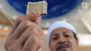 Kyai Tubagus Muhammad Tamyiz menunjukkan Alquran mini di Masjid Jami Darusalam, Sukaraja, Bogor, Kamis (24/5). Alquran mini itu seluruh aksaranya ditulis tangan menggunakan tinta emas serta ditulis di atas lembaran kulit kayu. (Merdeka.com/Arie Basuki)