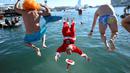 Para peserta tradisi lomba renang unik saat natal di pelabuhan tua Barcelona (Port Vell Barcelona), Spanyol, Senin (25/12/2023) waktu setempat. (AFP/Josep Lago)