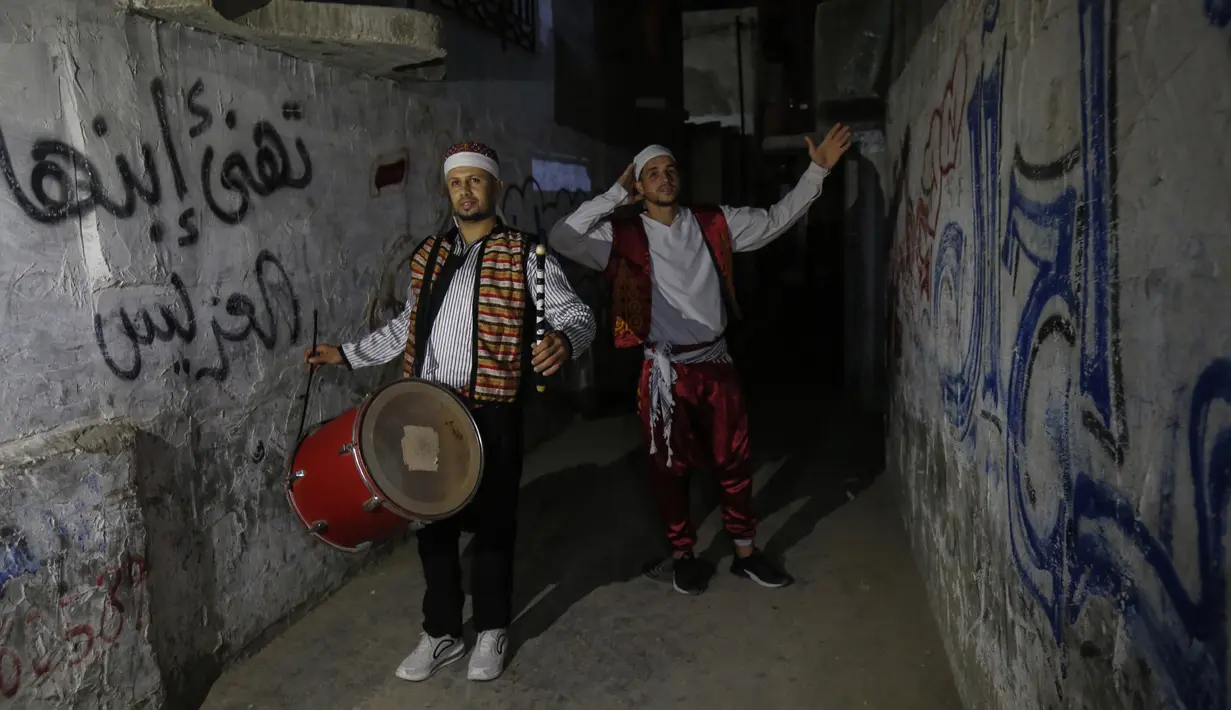 Dua pemuda "Musharati" Palestina memukul gendang saat membangunkan umat muslim untuk sahur pada malam kedua selama bulan suci Ramadan di Rafah di Jalur Gaza selatan (25/4/2020). (AFP/Said Khatib)