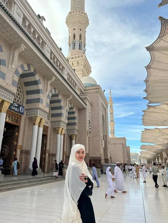 Aaliyah Massaid juga diketahui sedang menjalankan ibadah Umroh saat ini. Momen pertamanya menginjakkan kaki di Tanah Suci, terlihat Aaliyah juga menghadirkan penampilan santun tertutup. Ia mengeanakn abaya hitam dengan syal panjang berwarna putih polos yang dijadikan sebagai hijab. [Foto: Instagram/aaliyah.massaid]