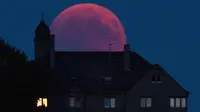 Bulan tampak berwarna merah darah saat terjadinya fenomena gerhana bulan total  di Bernkastel-Kues, Jerman, Jumat (27/7). Gerhana bulan yang terlama pada abad ini dapat disaksikan di seluruh dunia dengan mata telanjang. (Harald Tittel/dpa via AP)