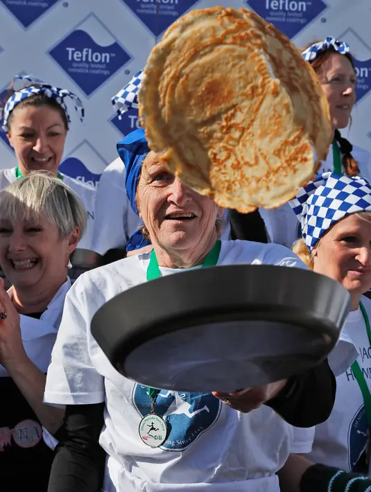 Peserta berkumpul setelah menyelesaikan lomba lari dengan membawa pancake dalam lomba tahunan Pancake Trans-Atlantic di Olney, Buckinghamshire, Inggris, Selasa (5/3). Peserta juga harus membolak-balikan pancake sambil tetap berlari. (AP/Frank Augstein)