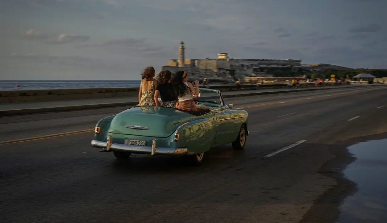 <p>Turis menaiki Malecon dengan mobil antik Amerika di Havana, Kuba, Senin (16/5/2022). Pemerintahan Presiden AS, Joe Biden mengumumkan akan melonggarkan pembatasan atas pengetatan yang diberlakukan selama pemerintahan Donald Trump terhadap Kuba dan mencabut batas saat ini $1.000 per kuartal yang dapat dikirim imigran kepada anggota keluarga yang masih tinggal di pulau itu. (AP Photo/Ramon Espinosa)</p>