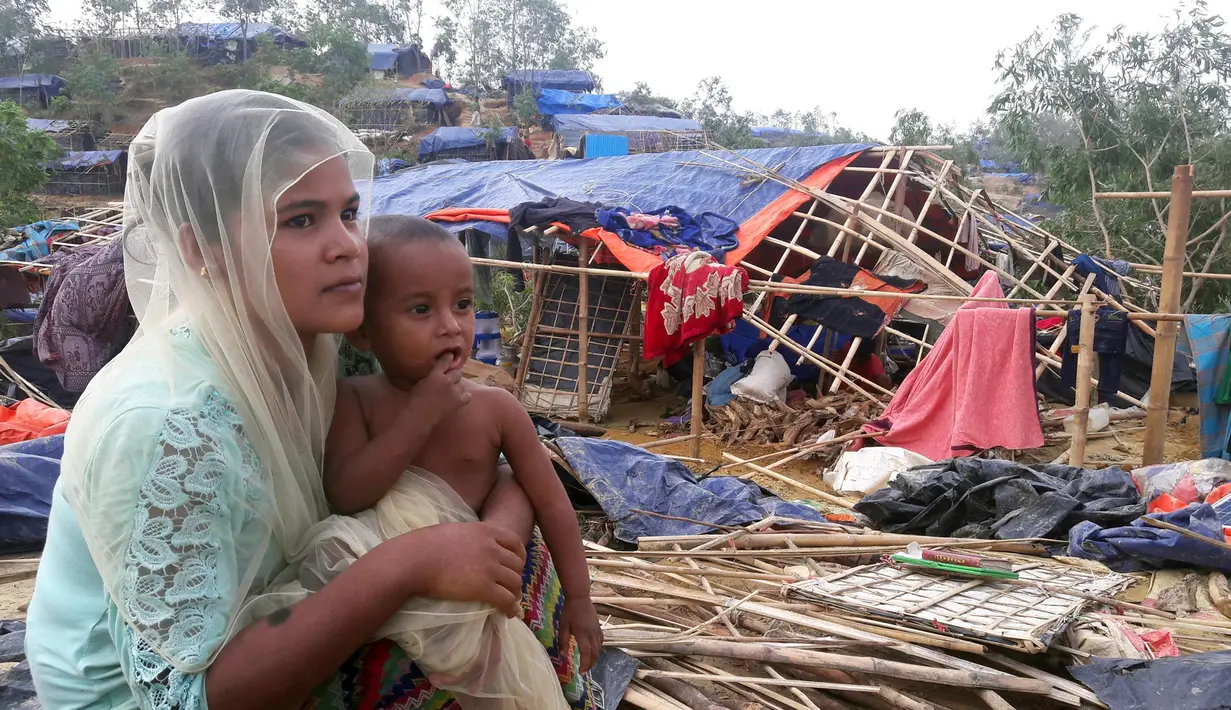 Pengungsi Rohingya duduk di dekat rumahnya setelah Topan Mora menghantam di sebuah kamp di distrik Cox's Bazar, Bangladesh (31/5). Ribuan rumah dan tenda-tenda yang beratap jerami di kamp tersebut hancur akibat Topan Mora. (AFP Photo/Str)