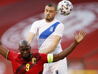 Striker Belgia, Romelu Lukaku, duel udara dengan pemain Yunani, Kyriakos Papadopoulos, pada laga uji coba di Stadion King Baudouin, Jumat (4/6/2021). Kedua tim bermain imbang 1-1. (AP/Francisco Seco)