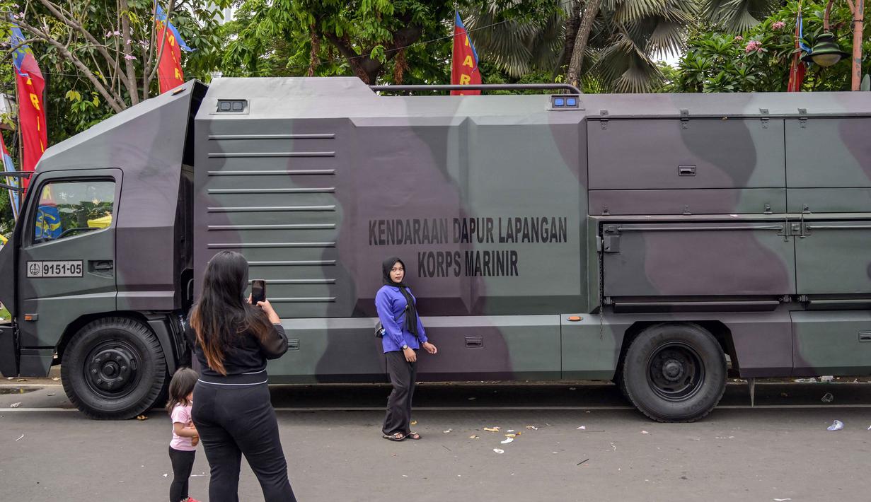 Kegiatan ini disambut antusias oleh masyakat, terutama anak-anak. Tampak dalam foto, warga berfoto bersama kendaraan militer selama Pameran Marinir Indonesia, yang menandai peringatan Hari Ulang Tahun ke-80 Korps Marinir TNI AL di Surabaya, Jawa Timur pada Minggu 9 November 2025. (JUNI KRISWANTO/AFP)