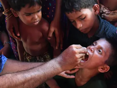 Seorang anak diberi vaksin kolera oleh sukarelawan Bangladesh di kamp pengungsi Thankhali di distrik Ukhia (10/10). Di tengah kekhawatiran wabah, PBB memberikan vaksinasi kolera untuk hampir satu juta orang Rohingya. (AFP Photo/Indranil Mukherjee)