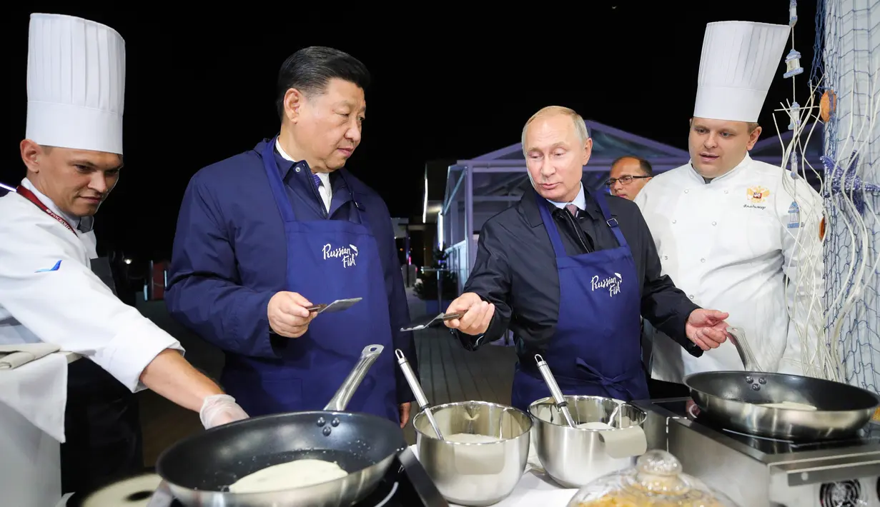 Presiden Rusia Vladimir Putin (dua kanan) berbincang dengan Presiden China Xi Jinping (kedua kiri) saat membuat pancake bersama di sela acara Eastern Economic Forum di Vladivostok, Rusia, Selasa (11/9). (Sergei Bobylev/TASS News Agency Pool Photo via AP)