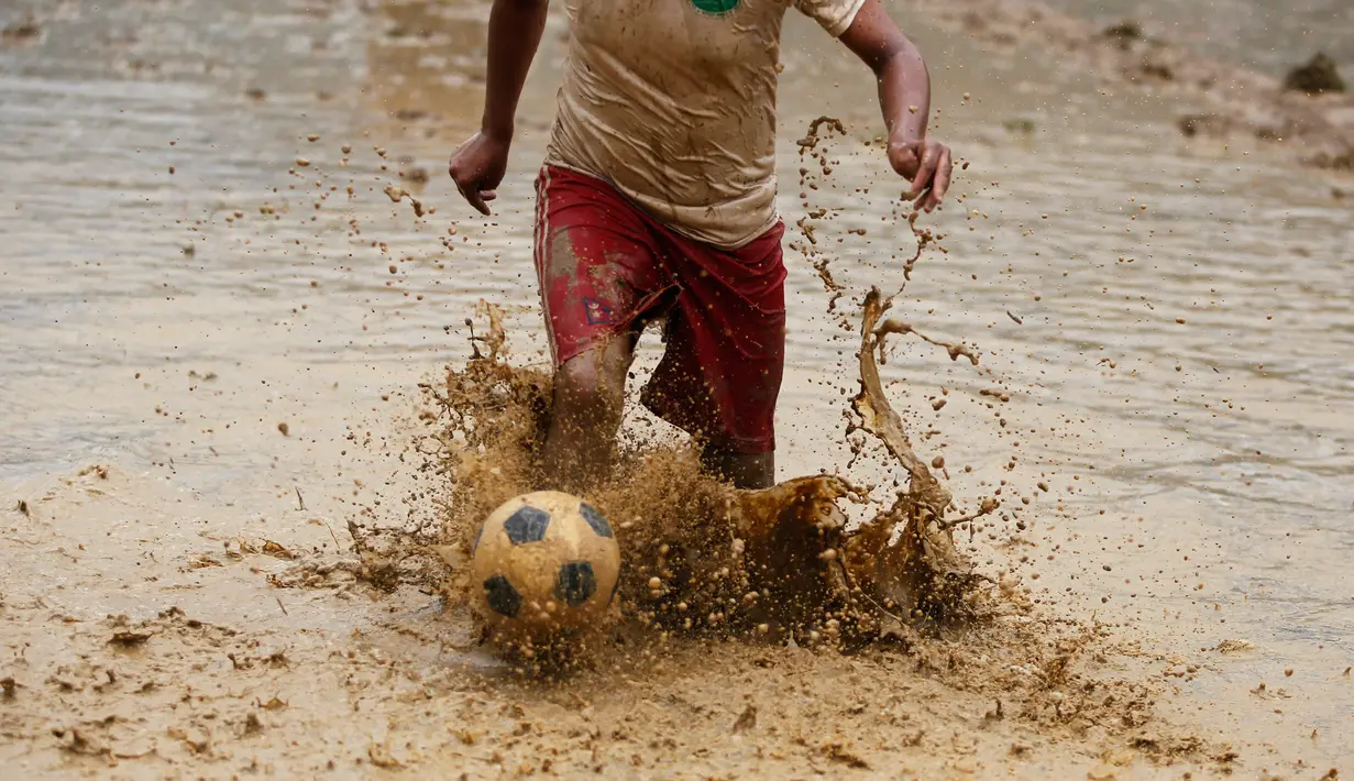 Seorang pria Nepal bermain bola di lumpur pada Asar Pandra, atau hari menanam padi nasional di Lalitpur, 29 Juni 2018. Asar Pandra diadakan sebagai tanda dimulainya kembali aktivitas tanam padi di sawah saat musim hujan tiba. (AP Photo/Niranjan Shrestha)