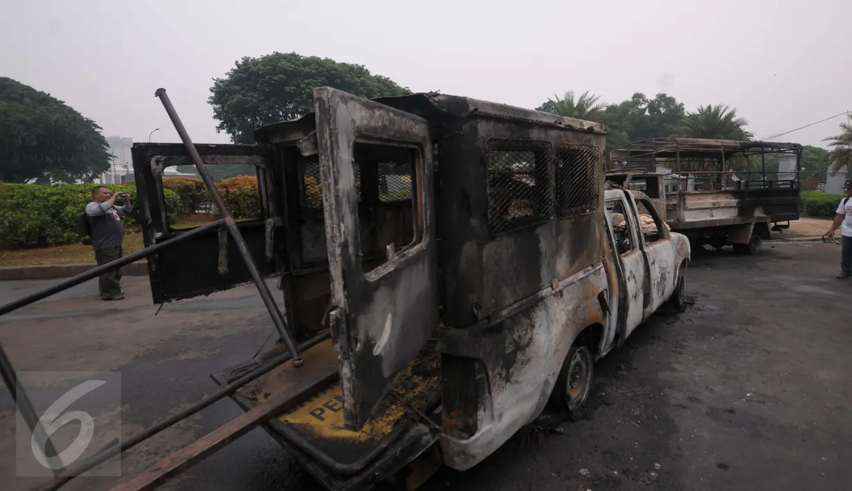 Sisa kendaraan milik kepolisian yang dibakar saat bentrokan di tengah demo 4 November, di kawasan Monas, Jakarta, Sabtu (5/11). Pengunjung menjadikan dua kendaraan milik kepolisianitu sebagai objek foto dan melakukan swafoto. (Liputan6.com/Angga Yuniar)