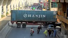 Sejumlah pengendara motor melewati kolong sebuah truk kontainer di Rawalpindi, Pakistan (28/10). Kejadian ini akibat sejumlah truk kontainer memblokir jalan raya selama demo yang digelar Awami Muslim League (AML). (Reuters/Faisal Mahmood)