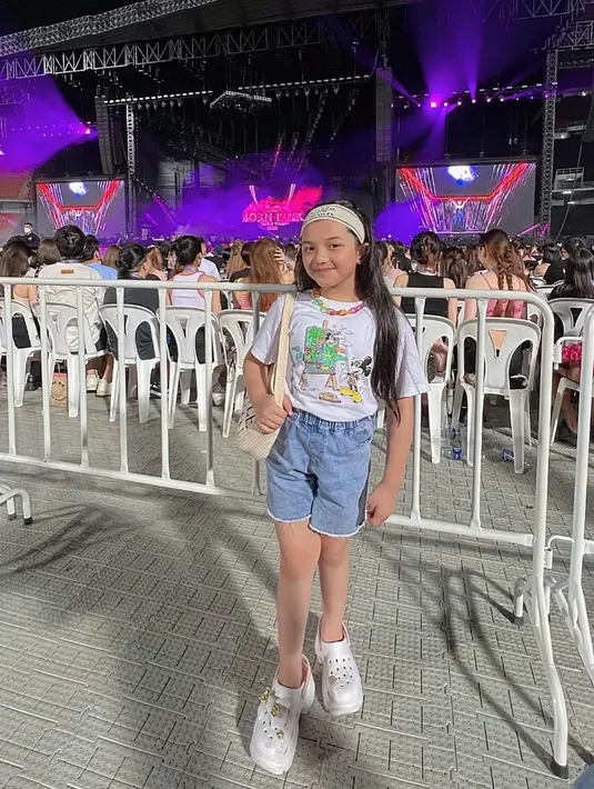 Menggemaskan, potret Arsy saat menonton konser BLACKPINK di Thailand. Bergaya bak remaja, Arsy mengenakan kaus putih bermotif dan celana jeans pendek, serta bandana. Foto: Instagram.