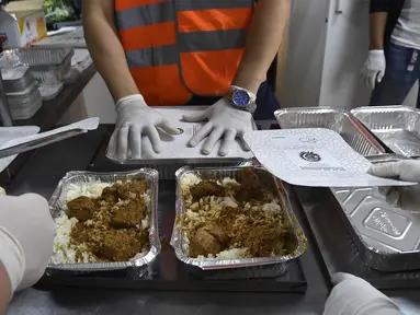 Relawan dari asosiasi Nass el-Khir mengemas kotak makanan sebelum didistribusikan kepada mereka yang membutuhkan selama bulan suci Ramadan di Aljir, Aljazair, Senin (18/5/2020). (RYAD KRAMDI/AFP)