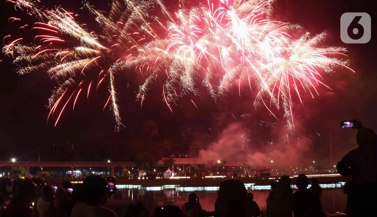 Warga menyaksikan pesta kembang api saat perayaan malam puncak Tahun Baru 2023 di Danau Archipelago, Taman Mini Indonesia Indah (TMII), Jakarta, Minggu (1/1/2023). Sebelumnya, Pemprov DKI Jakarta menunjuk TMII untuk menjadi pusat perayaan tahun baru 2023 di Jakarta. (Liputan6.com/Herman Zakharia)