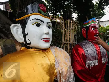 Pengrajin memperbaiki wajah ondel-ondel yang selesai dibuat di kawasan Kramat, Jakarta, Kamis (26/1). Ondel-ondel merupakan kesenian tradisional Betawi yang biasa ditampilkan dalam pesta-pesta atau hajatan. (Liputan6.com/Faizal Fanani)