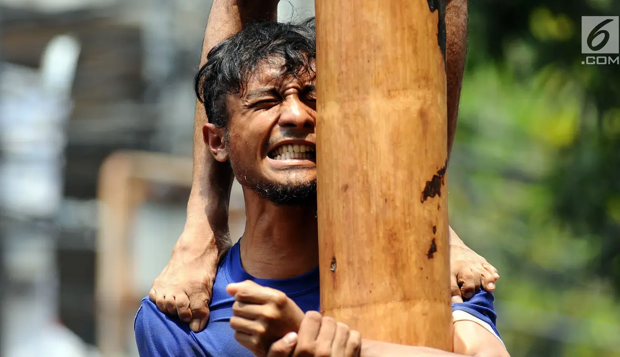 Salah satu peserta panjat pinang menahan beban rekannya saat mengikuti lomba di kawasan Jalan Jaksa, Jakarta, Kamis (17/8). Lomba diadakan untuk memeriahkan HUT RI ke-72. (Liputan6.com/Helmi Fithriansyah)