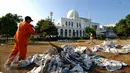 Beberapa petugas kebersihan membersihkan lapangan Lapangan Masjid Agung Al Azhar, Jakarta usai pelaksanaan salat Idul Fitri 1436 H, Jumat (17/7/2015). Sisa koran bekas dikumpulkan dan dimanfaatkan oleh pemulung. (Liputan6.com/Yoppy Renato)