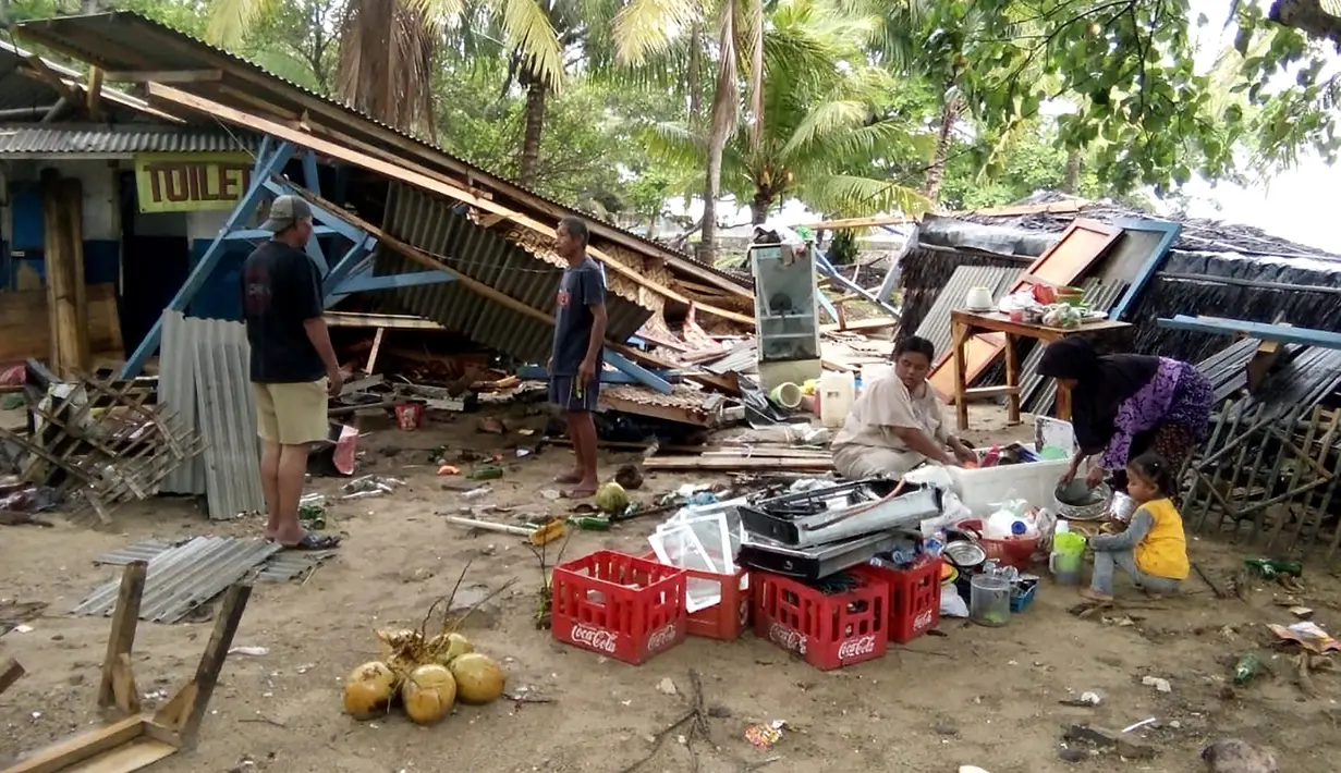 Warga mengumpulkan barang-barang dari bangunan yang rusak setelah tsunami menerjang Pantai Carita, di perairan Banten, Minggu (23/12). Tsunami menerjang pantai di Selat Sunda, khususnya di daerah Pandenglang, Lampung Selatan, dan Serang. (SEMI / AFP)