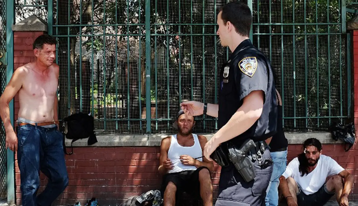Petugas polisi berdebat dengan para pecandu ganja sintetis saat hendak ditertibkan pinggir jalan East Harlem, New York (5/8/2015). Pada 2012 Amerika Serikat melarang pembuatan K2 atau ganja sintetis. (AFP PHOTO/SPENCER PLATT)