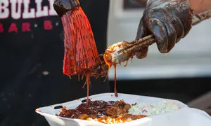 Koki menambahkan saus barbeku pada iga yang sudah dimasak dalam acara drive-thru Scarborough Ribfest 2020 di Toronto, Kanada, 27 September 2020. Pengunjung festival makanan yang digelar dalam format drive-thru itu dapat memesan makanan dari penjual di lokasi dan membawanya pulang. (Xinhua/Zou Zheng)