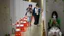 Jurnalis (kiri) yang mengenakan masker untuk mencegah penularan COVID-19 tiba untuk memberikan sampel air liur harian saat tes PCR di Pusat Media Olimpiade Tokyo 2020, Tokyo, Jepang, 20 Juli 2021. Jurnalis harus menjalani karantina mandiri selama dua minggu di negara asal. (Franck FIFE/AFP)