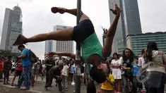 Pegiat 'Pole Dance' beraksi di tiang rambu lalu lintas saat Car Free Day di Bundaran HI, Jakarta, Minggu (18/1/2015). (Liputan6.com/Miftahul Hayat)