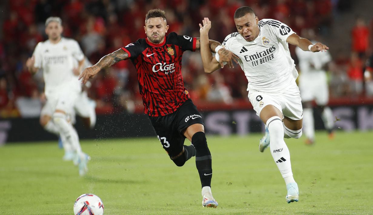 Pemain Real Madrid, Kylian Mbappe (kanan) berebut bola dengan pemain Real Mallorca, pada laga Liga Spanyol 2024/2025 di Mallorca Son Moix stadium, Spanyol, Senin (19/08/2024) dini hari WIB. (AFP/Jaime Reina)