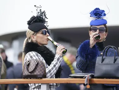 Dua wanita menikmati sampanye pada hari pertama Festival Cheltenham di Cheltenham Racecourse, Inggris, Selasa (15/3/2022). Kehadiran para wanita memberikan nuansa tersendiri di kompetisi pacuan kuda tersebut. (Mike Egerton/PA via AP)