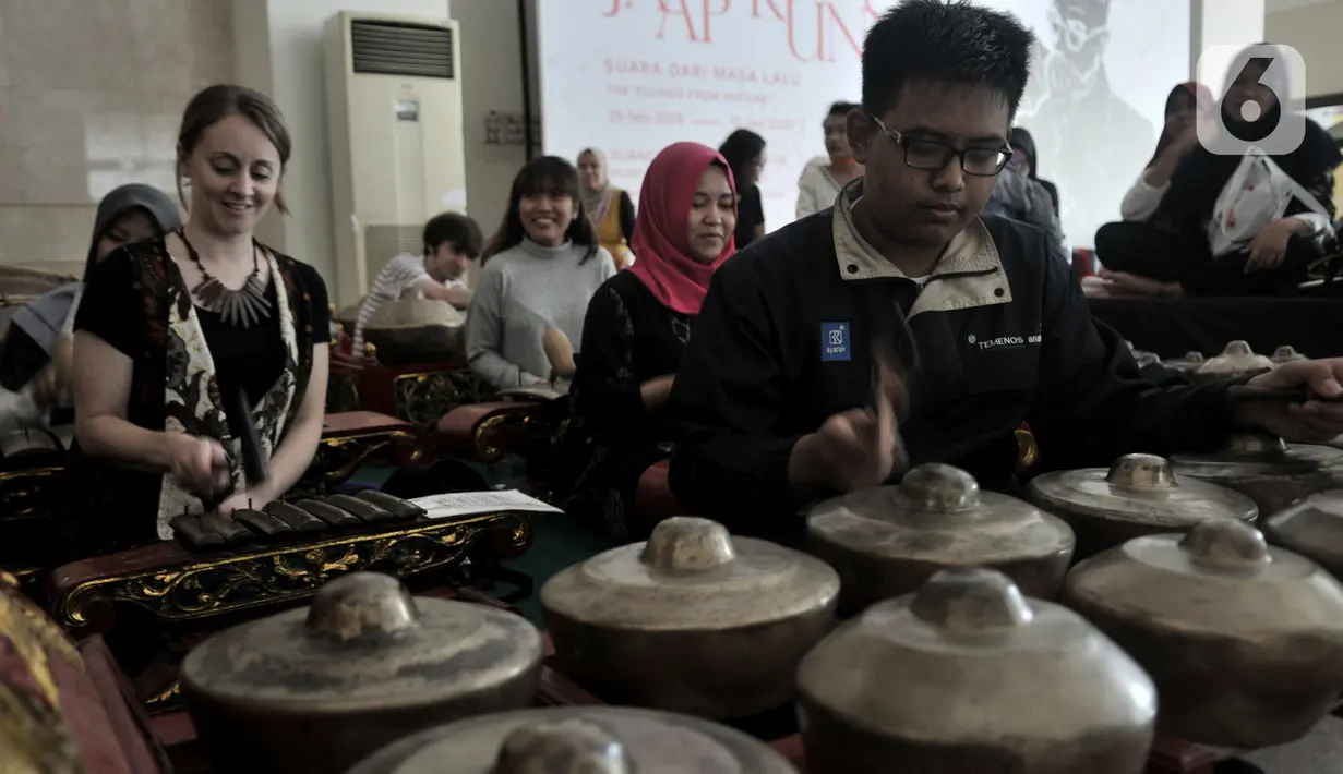 Wisatawan asing berlatih menjadi Nayaga saat lokakarya "Suara Dari Masa Lalu" di Museum Nasional, Jakarta, Minggu (22/12/2019). Lokakarya ini bertujuan mengenalkan sejarah gamelan dan mengajak generasi muda atau milenial mampu melestarikan musik tradisional Indonesia. (merdeka.com/Iqbal S. Nugroho)