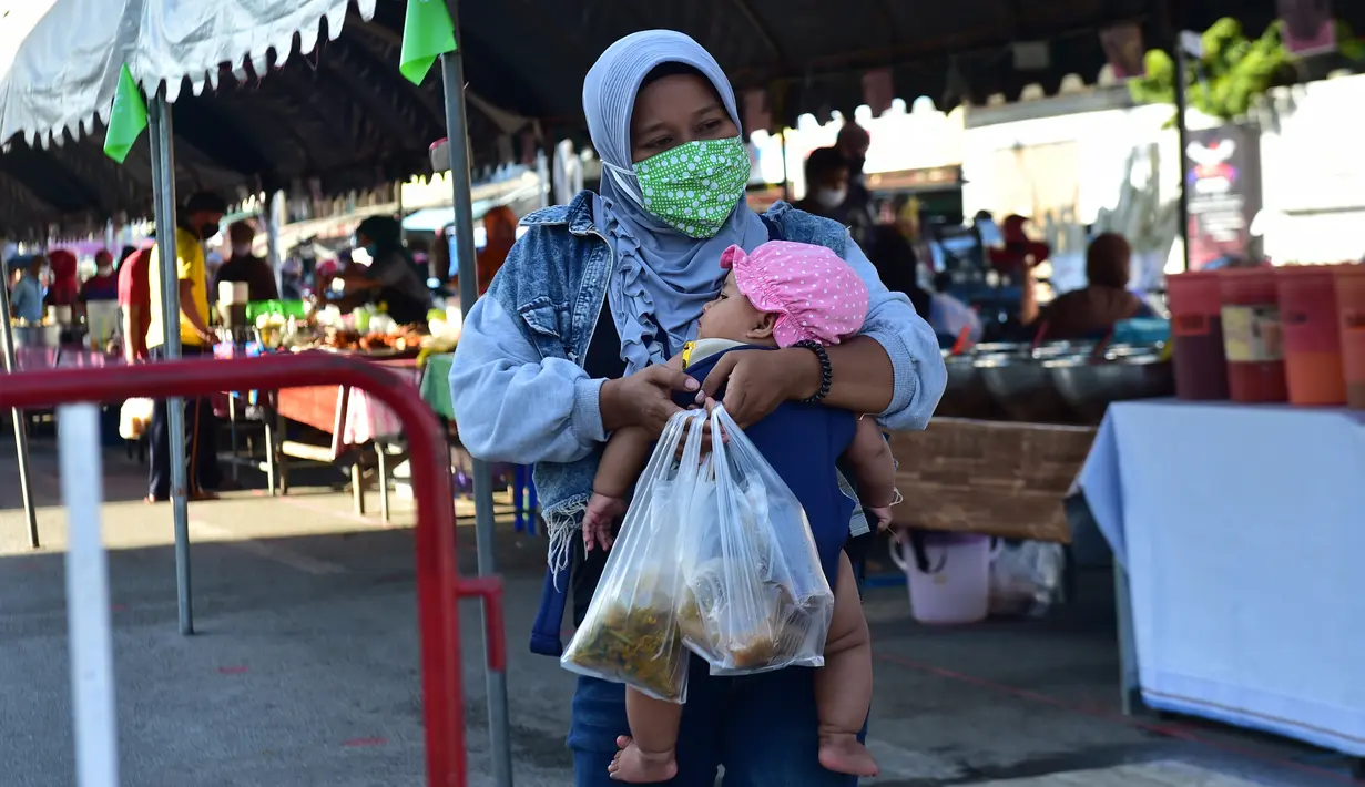 Seorang wanita yang mengenakan masker menggendong anaknya saat membeli makanan di pasar menjelang berbuka puasa selama bulan suci Ramadan di Provinsi Narathiwat, Thailand, Selasa (5/5/2020). Ramadan kali ini berlangsung di tengah bayang-bayang virus corona COVID-19. (Madaree TOHLALA/AFP)