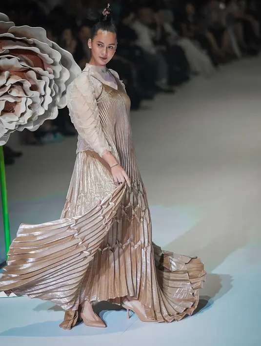 Busana ini dipadukan dengan spagetti strap pleated A-line gown berwarna kecokelatan [@paulaverhoeven]